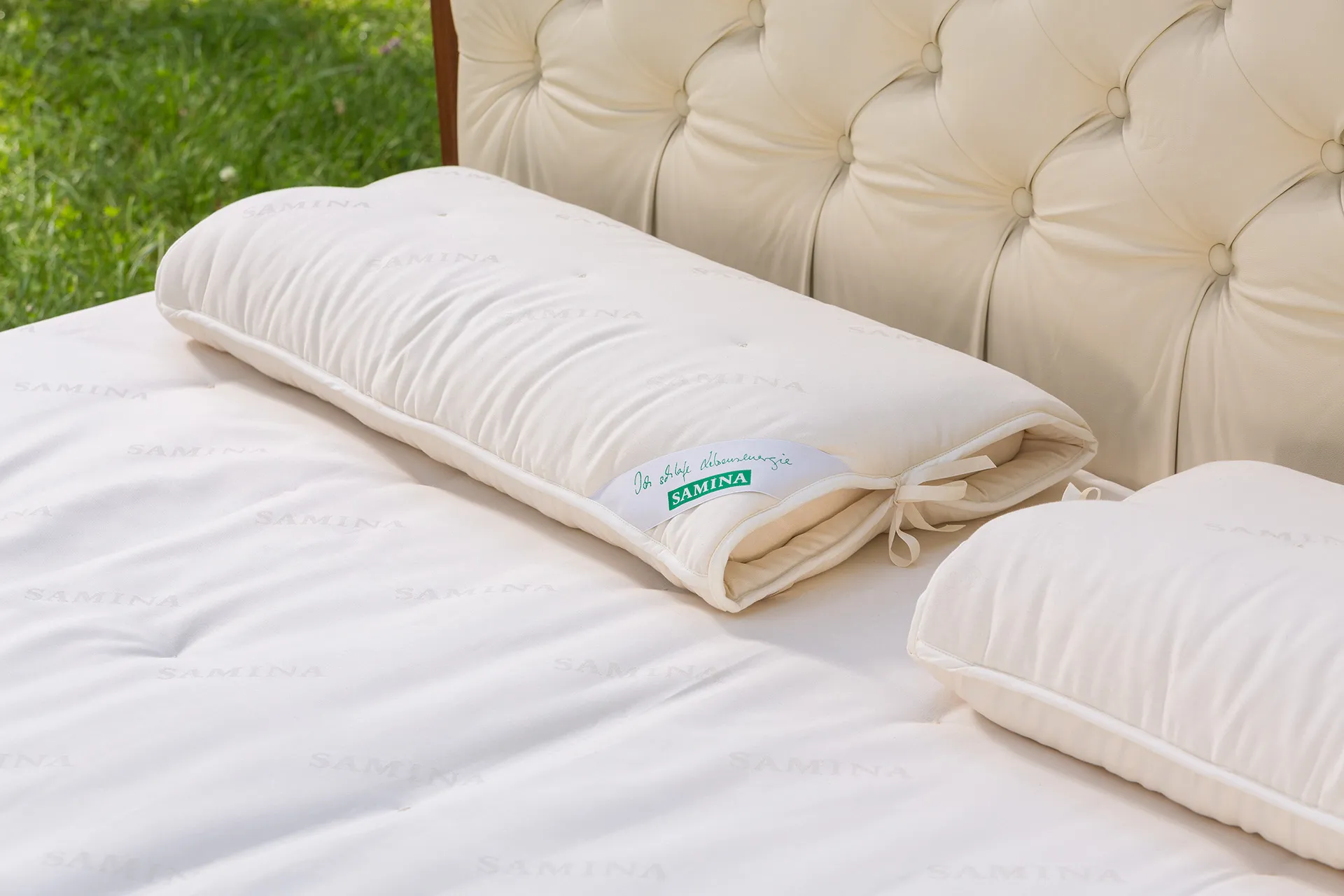 Bett mit gepolstertem Kopfteil und hellen Kissen in einem Garten Bett mit gepolstertem Kopfteil und hellen Kissen in einem Garten