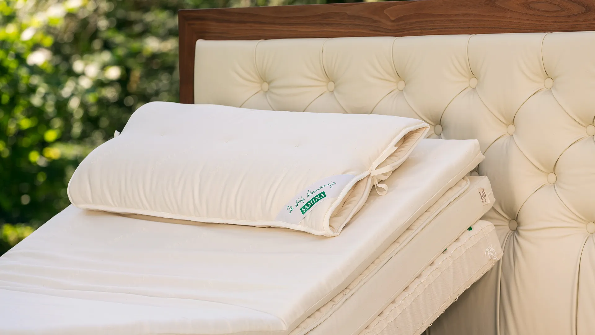 Bed with an upholstered headboard and light pillows in a garden Bed with an upholstered headboard and light pillows in a garden