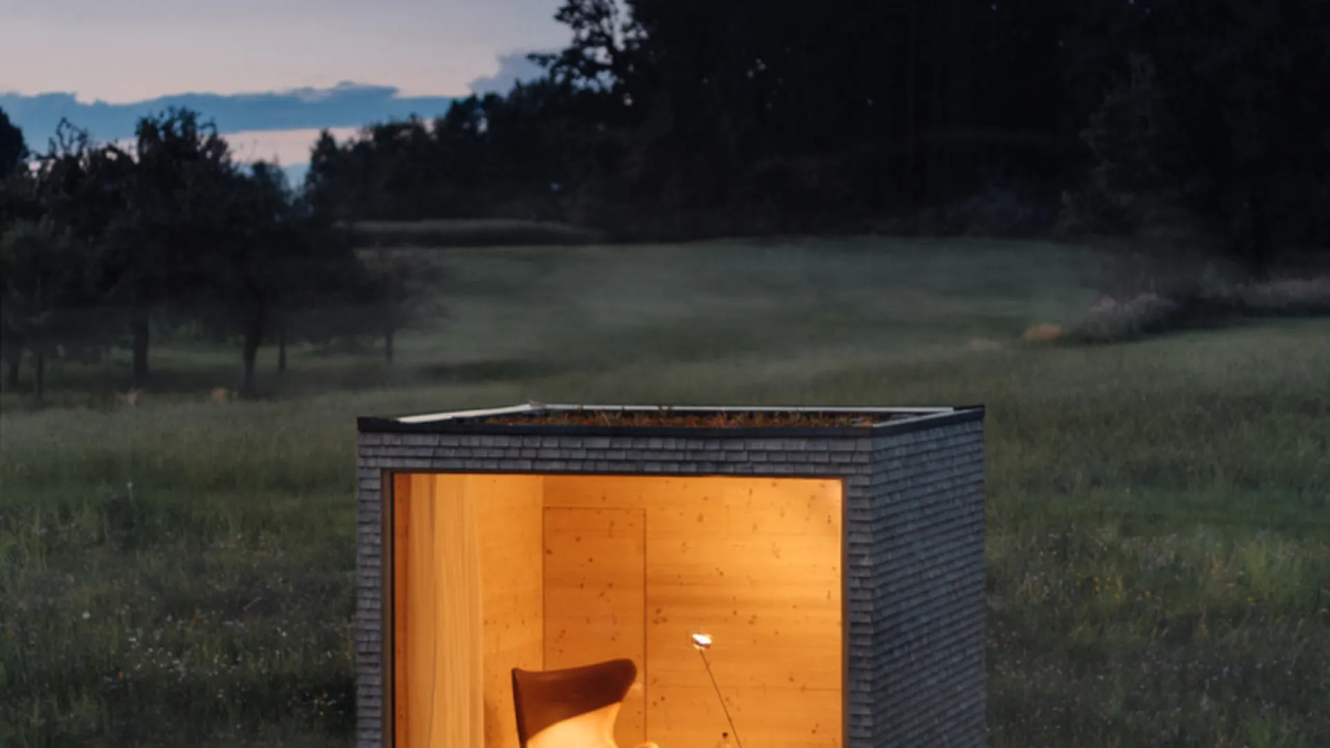 Illuminated garden room with a large square window at dusk