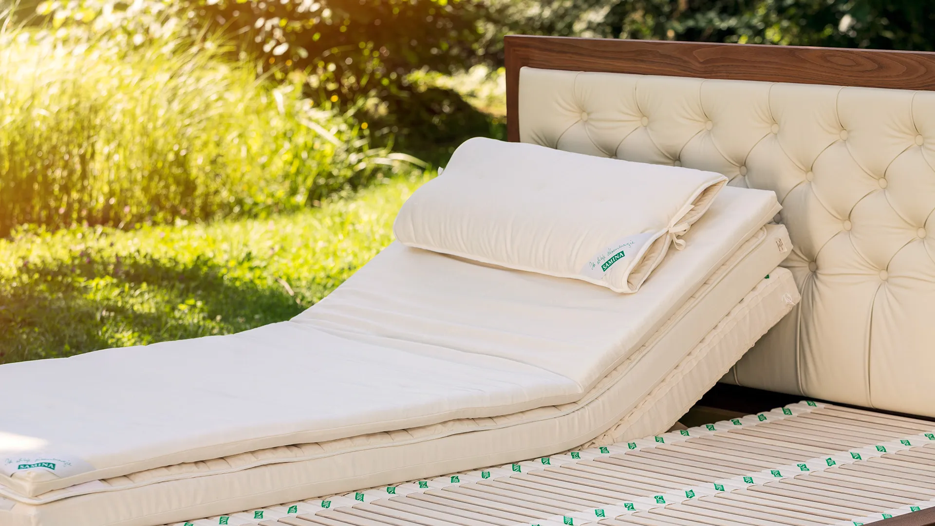 Bed with an upholstered headboard and light pillows in a garden Bed with an upholstered headboard and light pillows in a garden