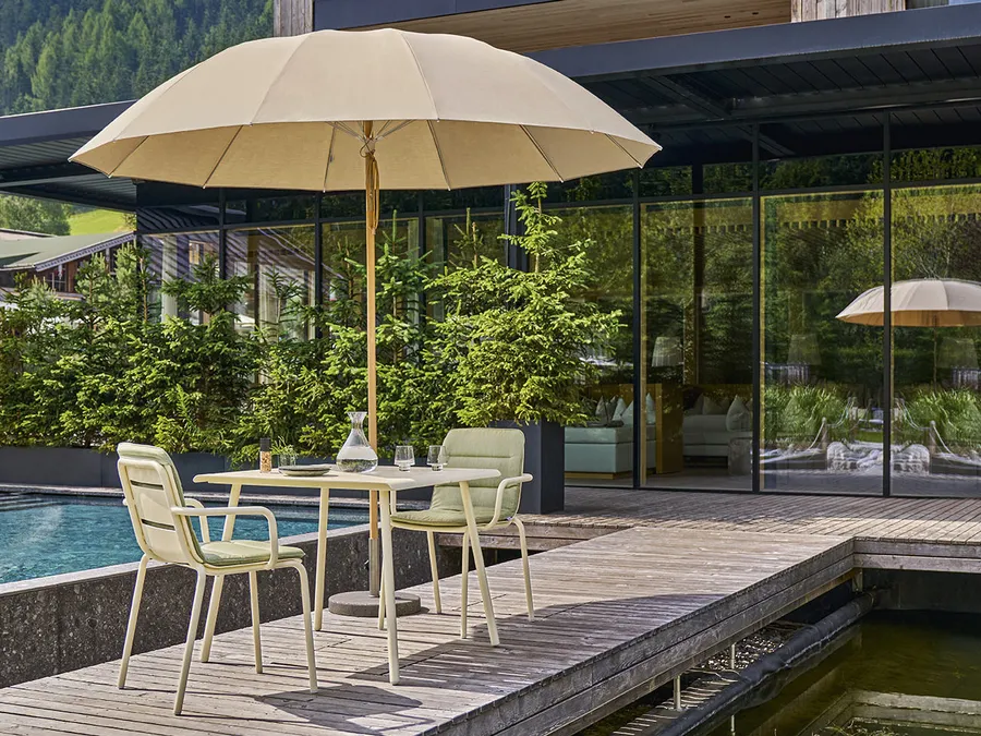 Sonnenschirm über Gartenmöbeln neben einer Terrasse Sonnenschirm über Gartenmöbeln neben einer Terrasse