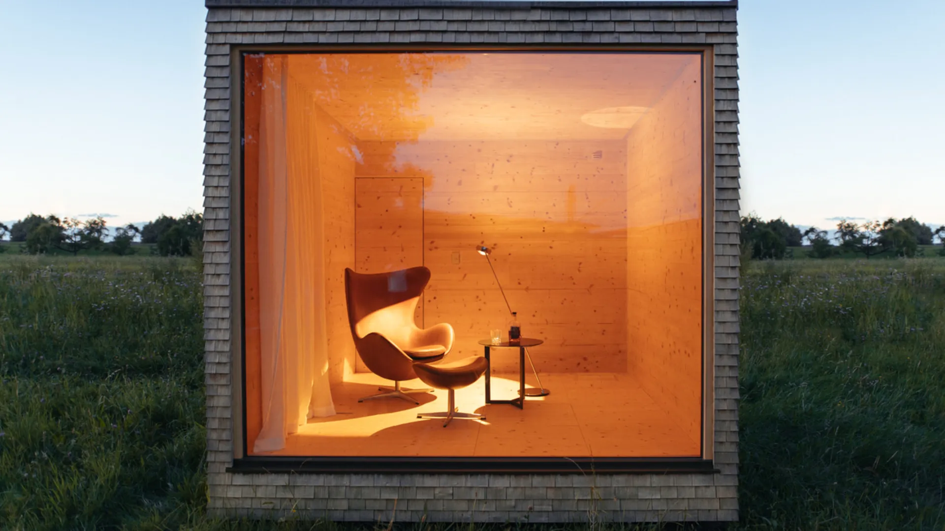 Beleuchtetes Gartenhaus mit großer quadratischer Fensterfront in der Abenddämmerung Beleuchtetes Gartenhaus mit großer quadratischer Fensterfront in der Abenddämmerung