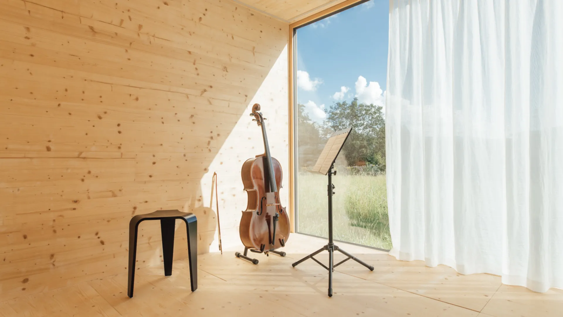 Musikinstrumente und Hocker vor einem großen Fenster in einem Holzraum Musikinstrumente und Hocker vor einem großen Fenster in einem Holzraum