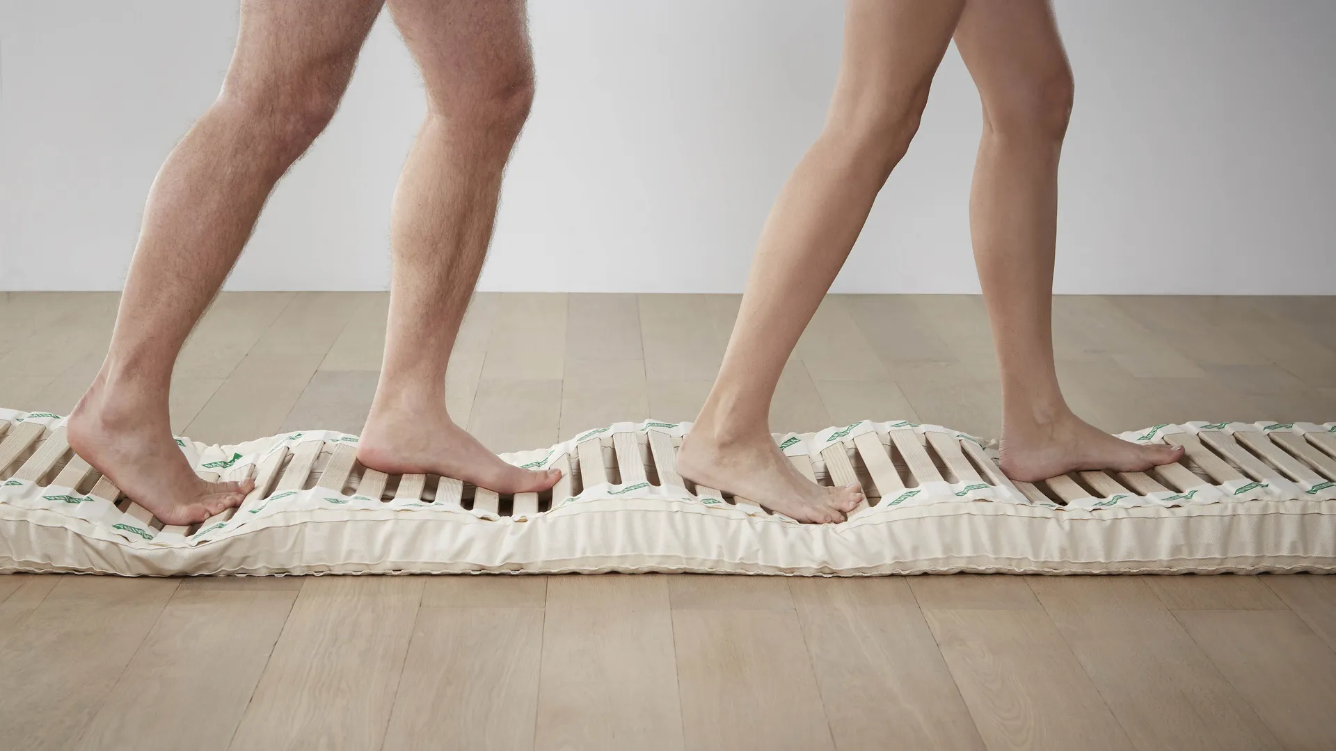 People standing on a flexible wooden slatted bed base People standing on a flexible wooden slatted bed base