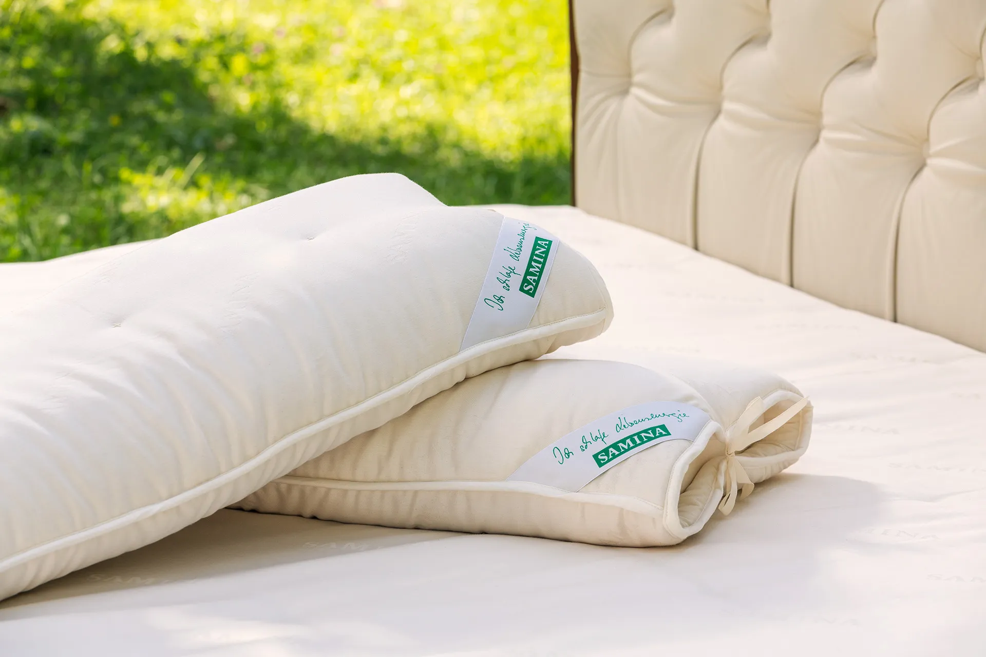 Bett mit gepolstertem Kopfteil und hellen Kissen in einem Garten Bett mit gepolstertem Kopfteil und hellen Kissen in einem Garten